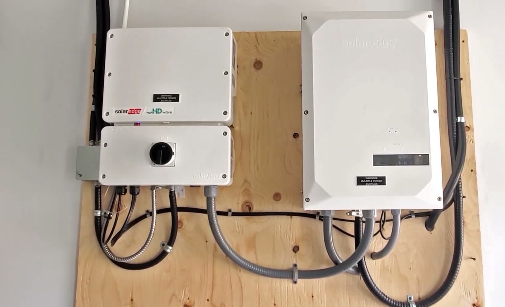 Solar inverters and disconnects mounted on a backboard after an install