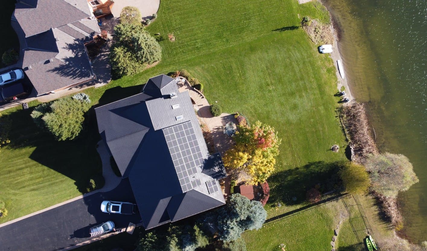 Drone view of a lakeside home with a KAJK solar array on its roof